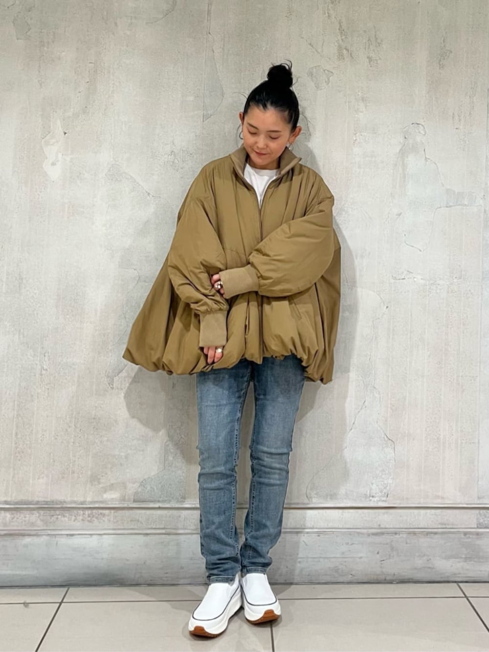 ホワイト系のスニーカー、ブルー系のデニムパンツ、イエロー系のその他アウターを着用したレディースの冬コーディネートの2枚目の写真