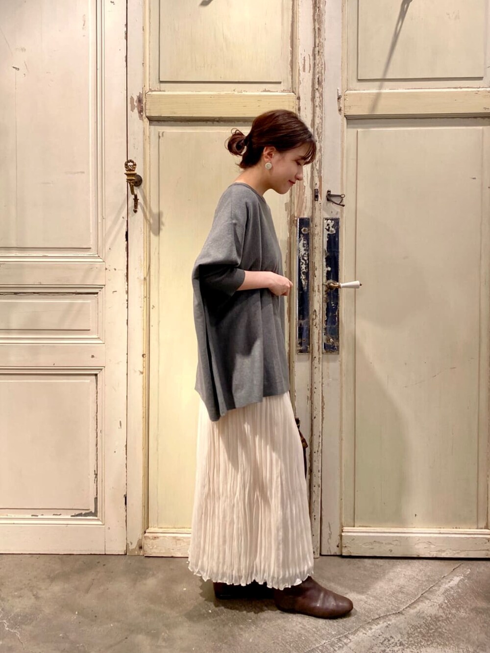 グレー系のニット/セーター、ホワイト系のスカート、ブラウン系のブーツを着用したレディースの秋コーディネートの2枚目の写真