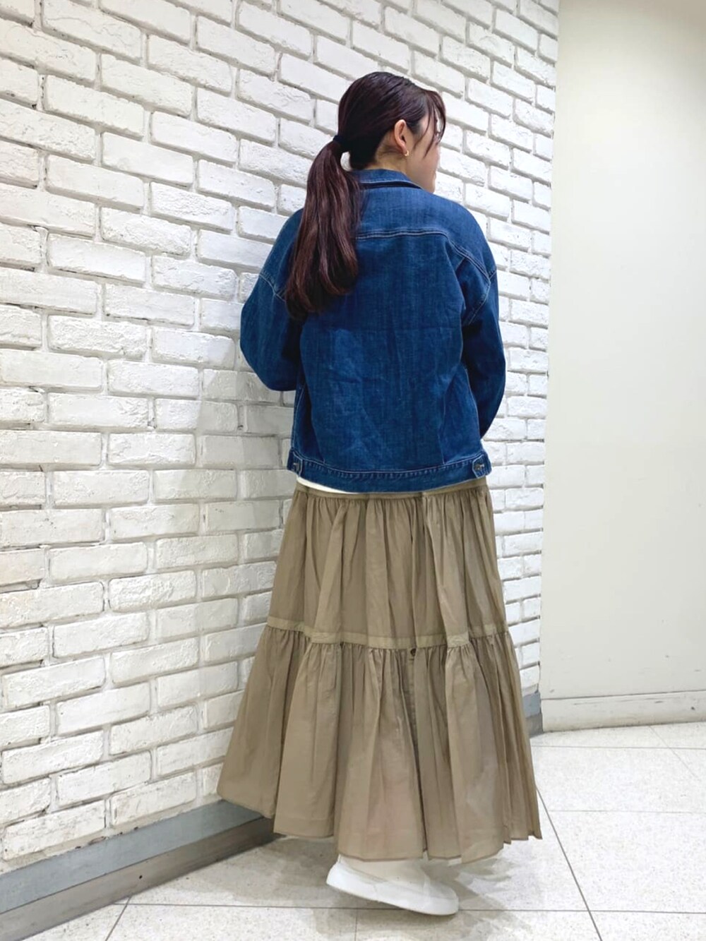 ブルー系のデニムジャケット、ホワイト系のTシャツ/カットソー、ベージュ系のスカートを着用したレディースの冬コーディネートの3枚目の写真