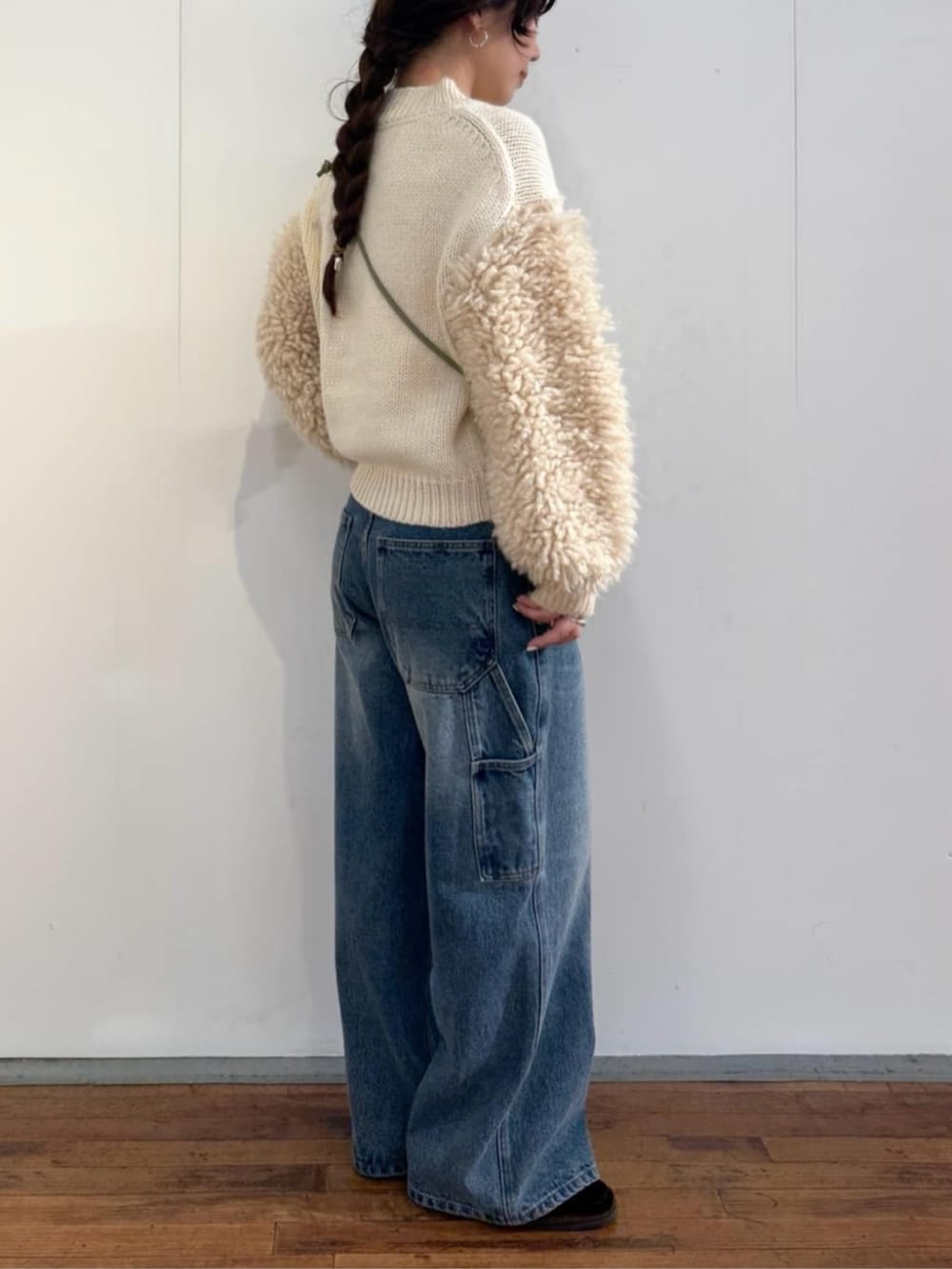 ブルー系のデニムパンツ、ホワイト系のニット/セーター、グリーン系のポーチを着用したレディースの秋コーディネートの5枚目の写真