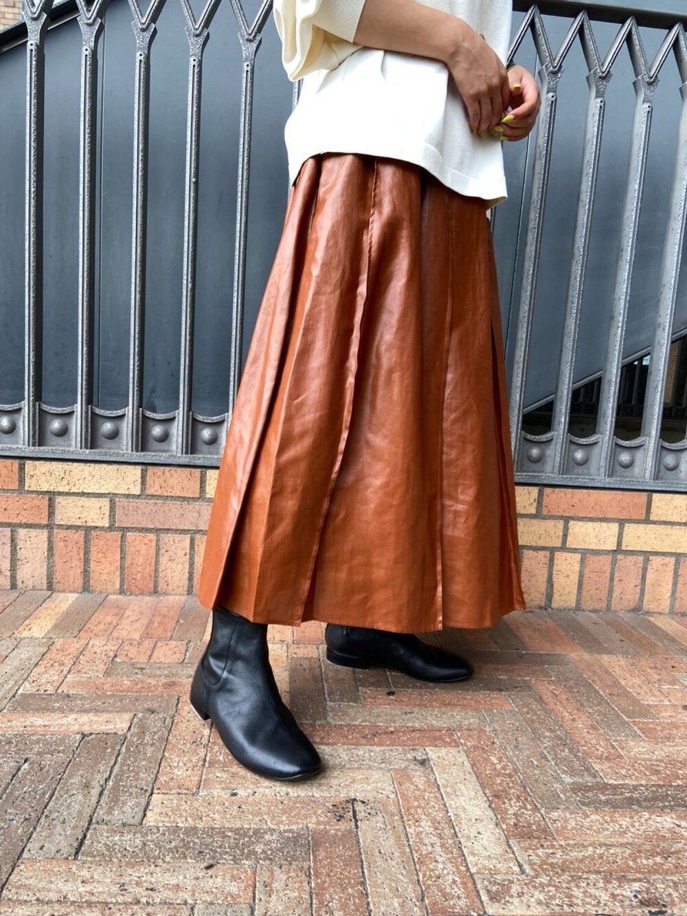 ホワイト系のニット/セーター、イエロー系のスカート、ブラック系のブーツを着用したレディースの秋コーディネートの4枚目の写真