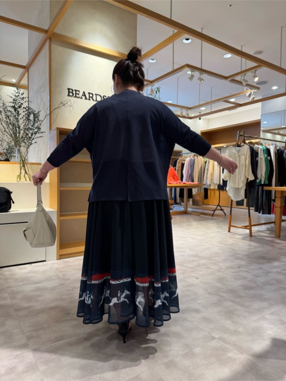 ホワイト系のトートバッグ、ブルー系のカーディガン/ボレロ、ブルー系のスカートを着用したレディースの春コーディネートの5枚目の写真