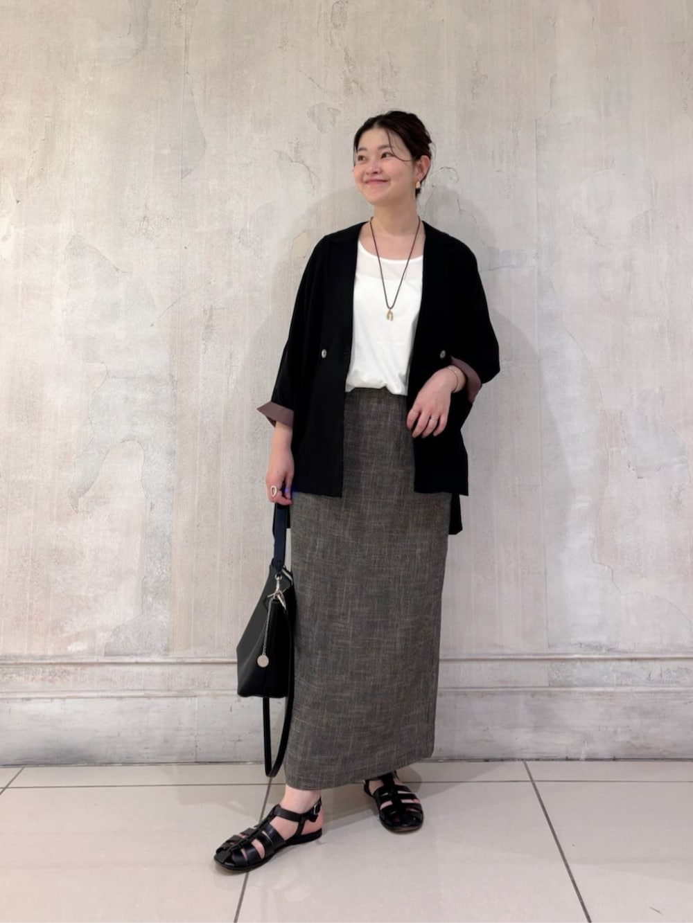 ブラック系のテーラードジャケット、ホワイト系のシャツ/ブラウス、ベージュ系のスカートを着用したレディースの春コーディネートの2枚目の写真