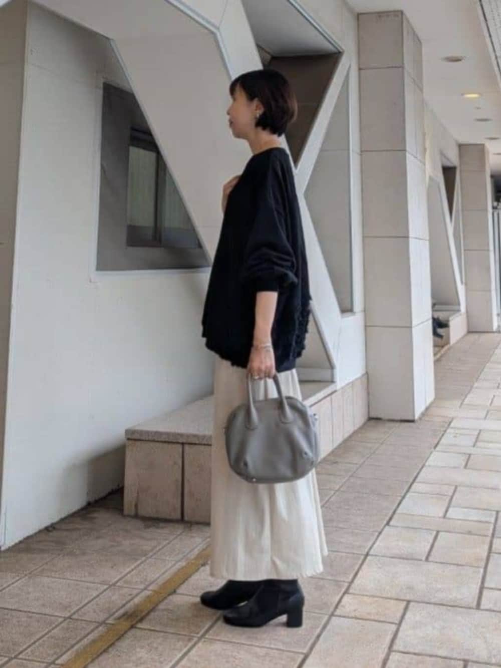 ベージュ系のスカート、ブラック系のTシャツ/カットソー、グレー系のトートバッグを着用したレディースの秋コーディネートの2枚目の写真