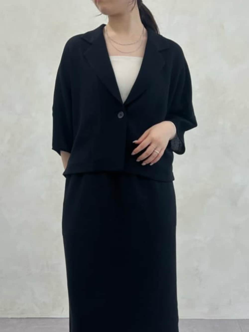 グレー系のハンドバッグ、ブラック系のテーラードジャケット、ブラック系のスカートを着用したレディースの春コーディネートの4枚目の写真