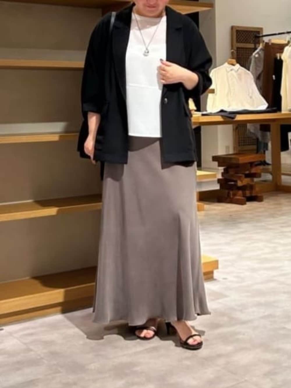 グリーン系のスカート、ブラック系のテーラードジャケット、ホワイト系のシャツ/ブラウスを着用したレディースの春コーディネートの2枚目の写真