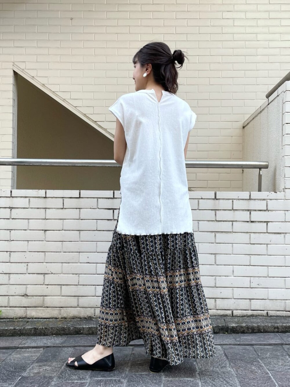 ホワイト系のTシャツ/カットソー、ブラック系のスカート、ブラック系のサンダルを着用したレディースの夏コーディネートの3枚目の写真