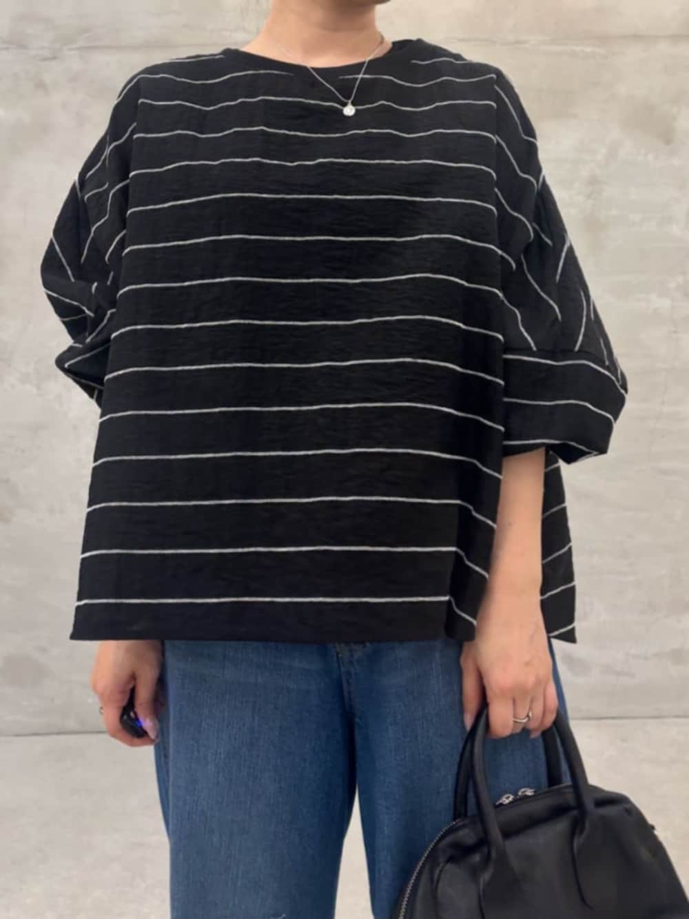 ブラック系のボストンバッグ、ブルー系のその他パンツ、ブラック系のシャツ/ブラウスを着用したレディースの春コーディネートの4枚目の写真