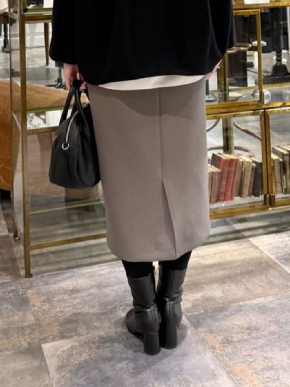 ブラウン系のスカート、ブラック系のノーカラーコートを着用したレディースの冬コーディネートの5枚目の写真