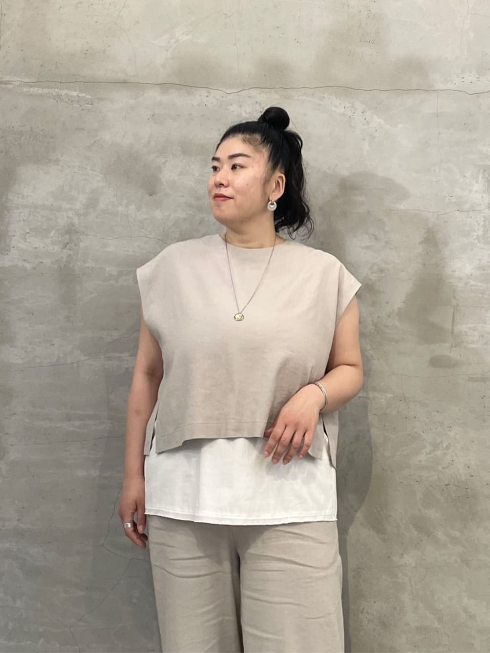 ホワイト系のタンクトップ、ブラック系のショルダーバッグ、ブラック系のサンダルを着用したレディースの春コーディネートの5枚目の写真