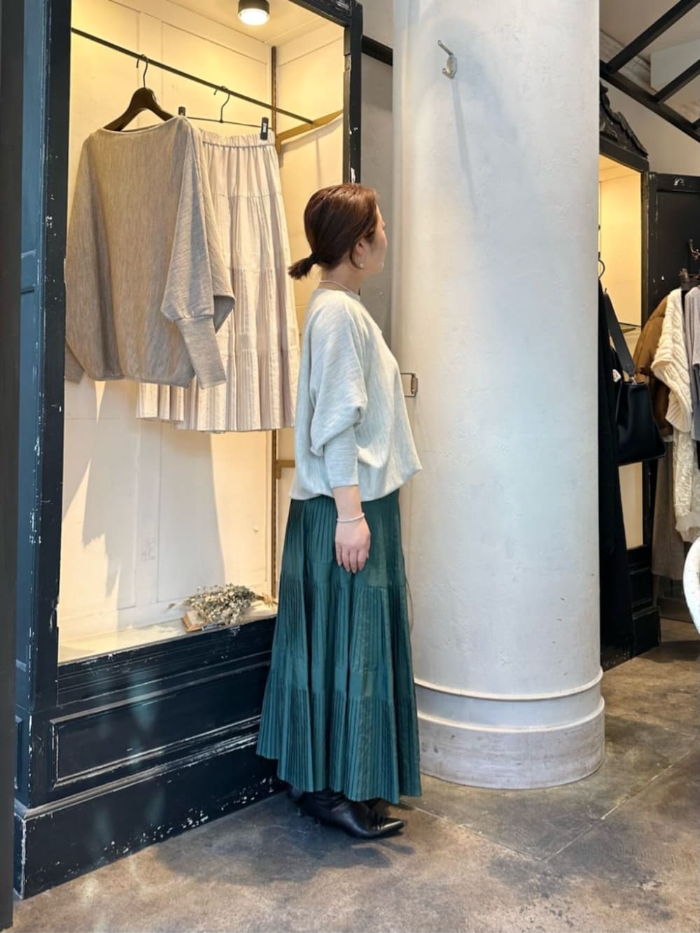 グリーン系のスカート、グレー系のニット/セーター、ブラック系のダウンジャケット/コートを着用したレディースの冬コーディネートの7枚目の写真