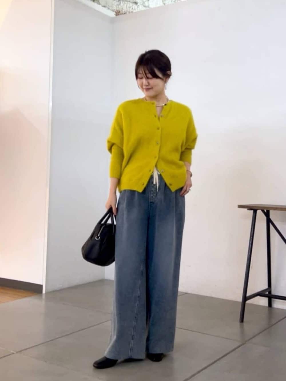 ブラック系のトートバッグ、イエロー系のニット/セーター、ブルー系のその他パンツを着用したレディースの秋コーディネートの2枚目の写真