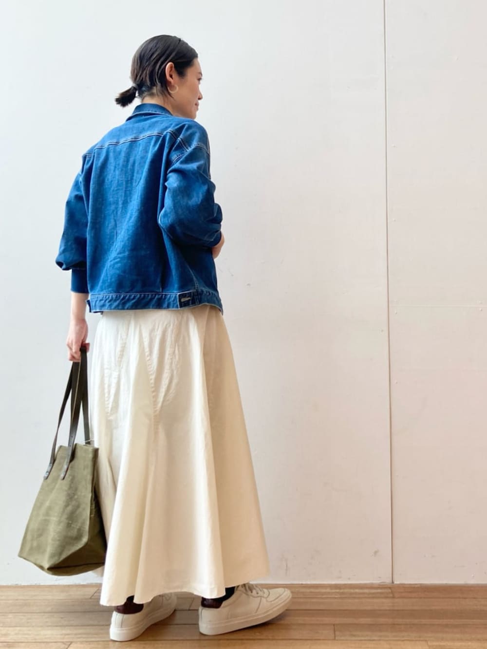 ブルー系のデニムジャケット、ブラック系のTシャツ/カットソー、ホワイト系のスカートを着用したレディースの冬コーディネートの3枚目の写真