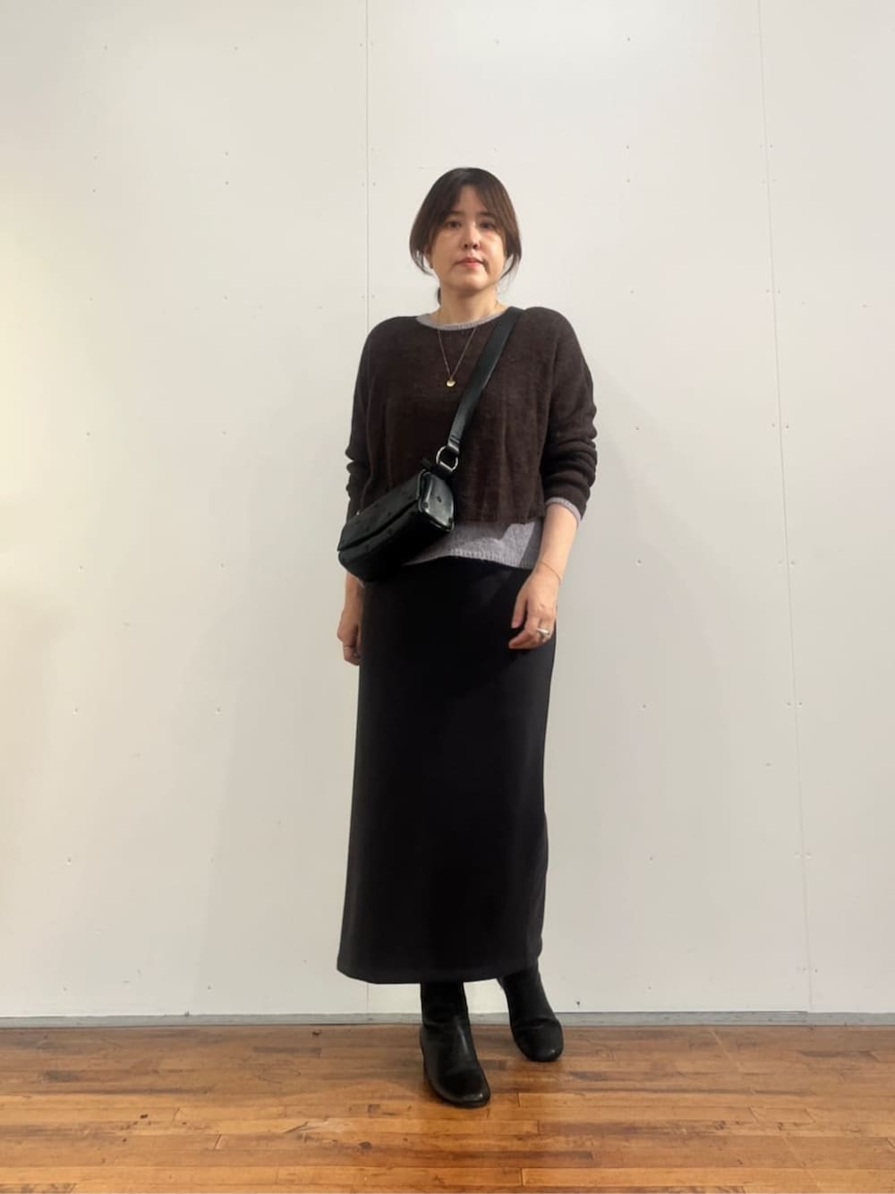 グレー系のスカート、ブラック系のショルダーバッグ、ブラウン系のニット/セーターを着用したレディースの夏コーディネートの2枚目の写真