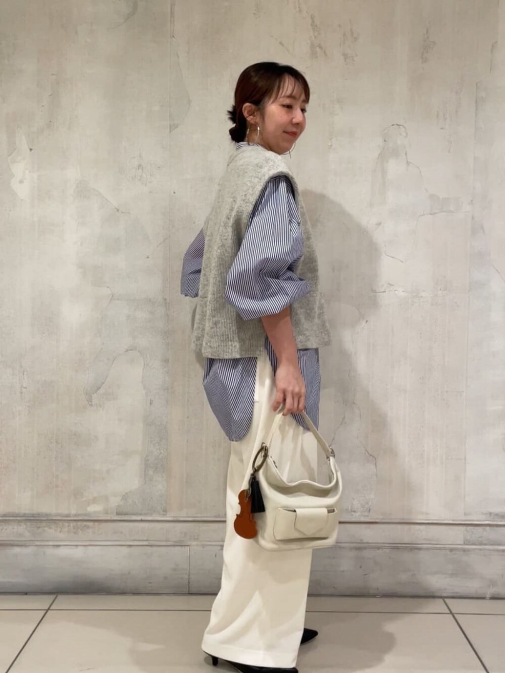 ブラック系のパンプス、ホワイト系のトートバッグ、グレー系のシャツ/ブラウスを着用したレディースの冬コーディネートの2枚目の写真