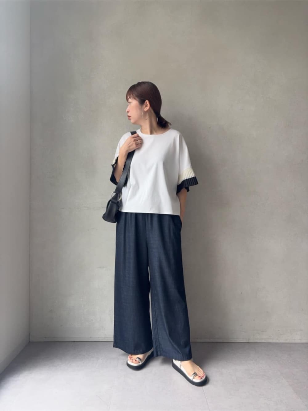 ブルー系のその他パンツ、ブラック系のショルダーバッグ、ホワイト系のサンダルを着用したレディースの春コーディネートの2枚目の写真