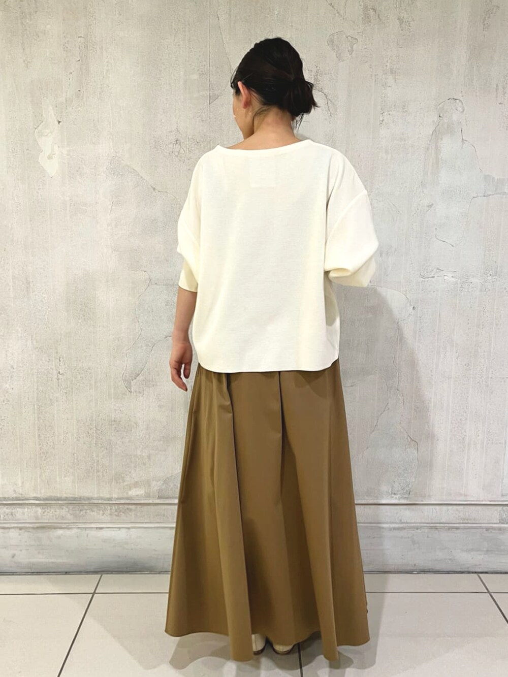 イエロー系のスカート、ホワイト系のニット/セーター、ベージュ系のバレエシューズを着用したレディースの冬コーディネートの4枚目の写真