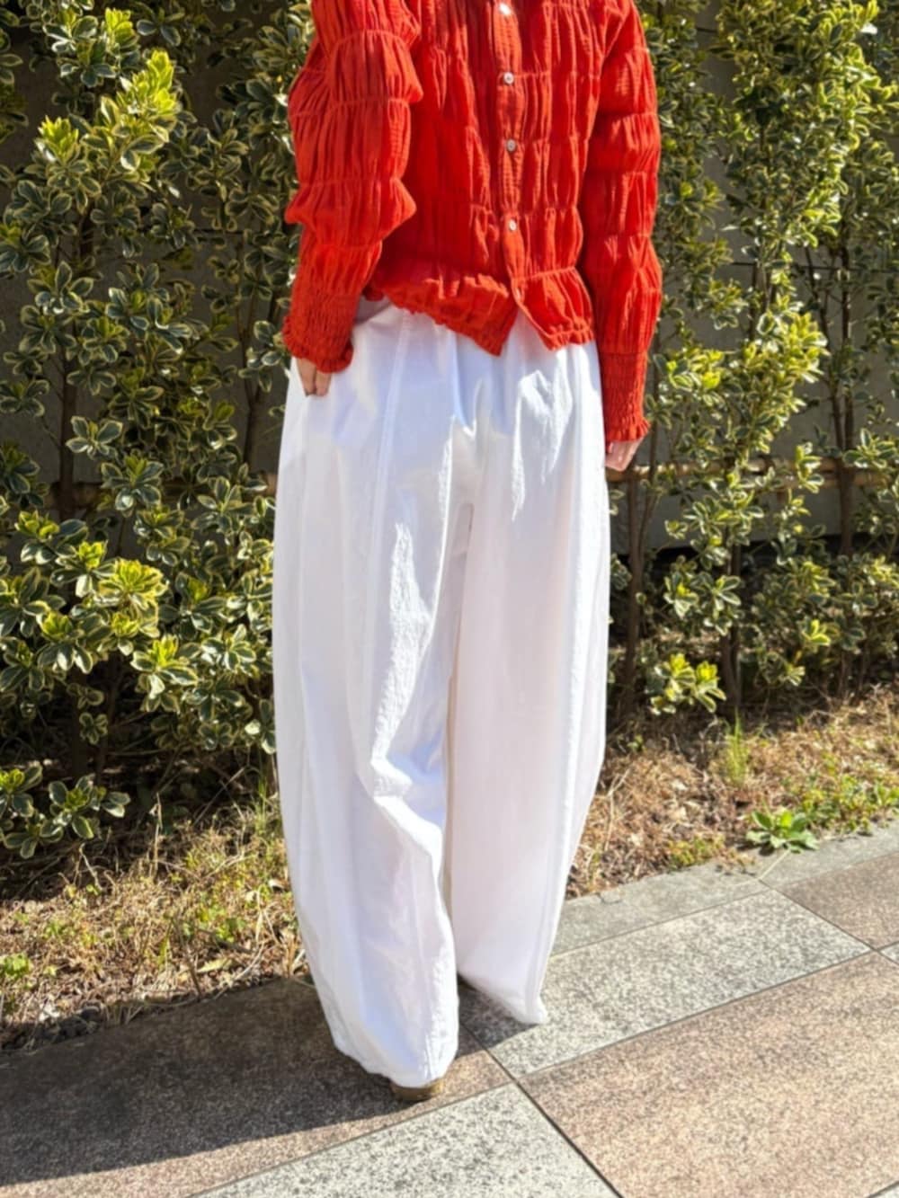 オレンジ系のシャツ/ブラウス、ホワイト系のその他パンツを着用したレディースの春コーディネートの10枚目の写真