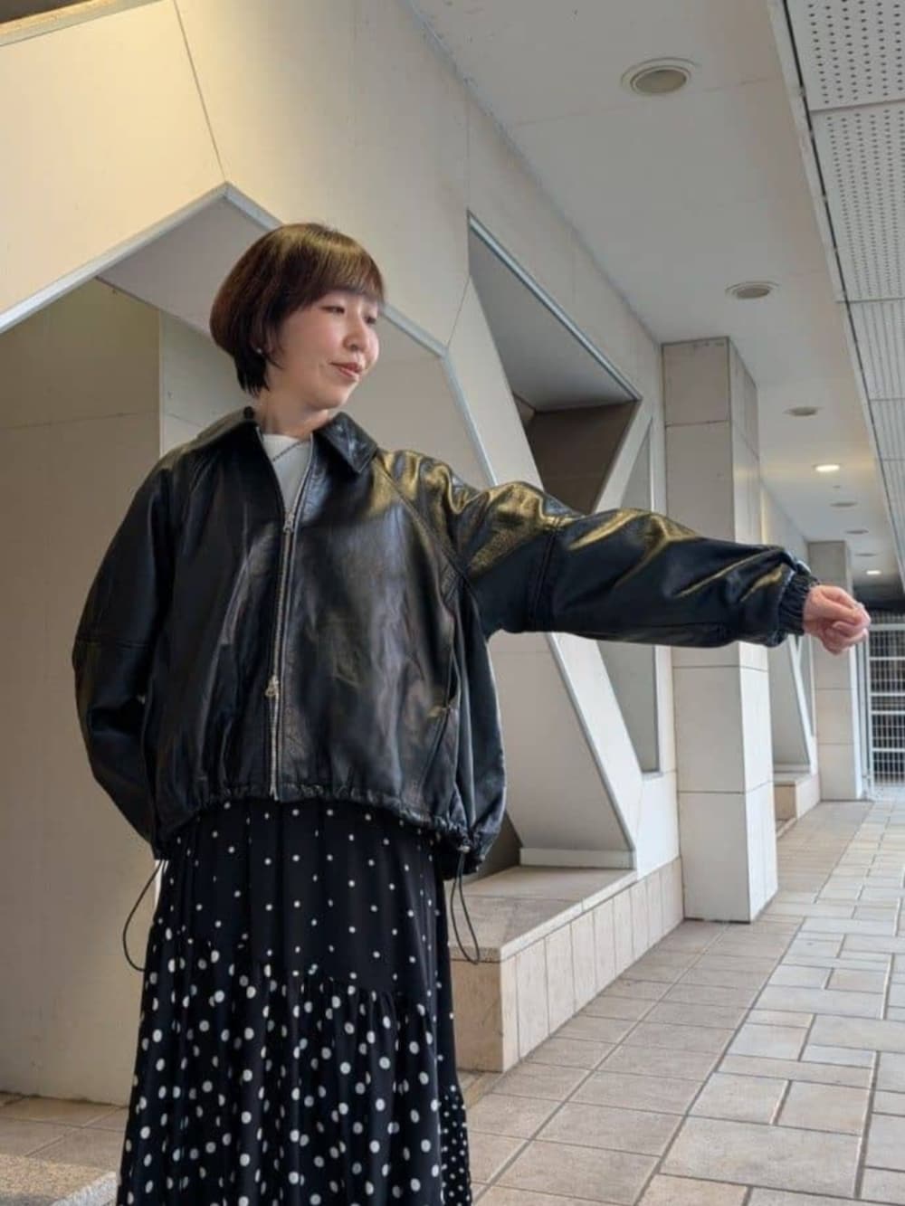 グリーン系のハンドバッグ、ブラック系のスカート、ブラック系のブルゾンを着用したレディースの冬コーディネートの5枚目の写真