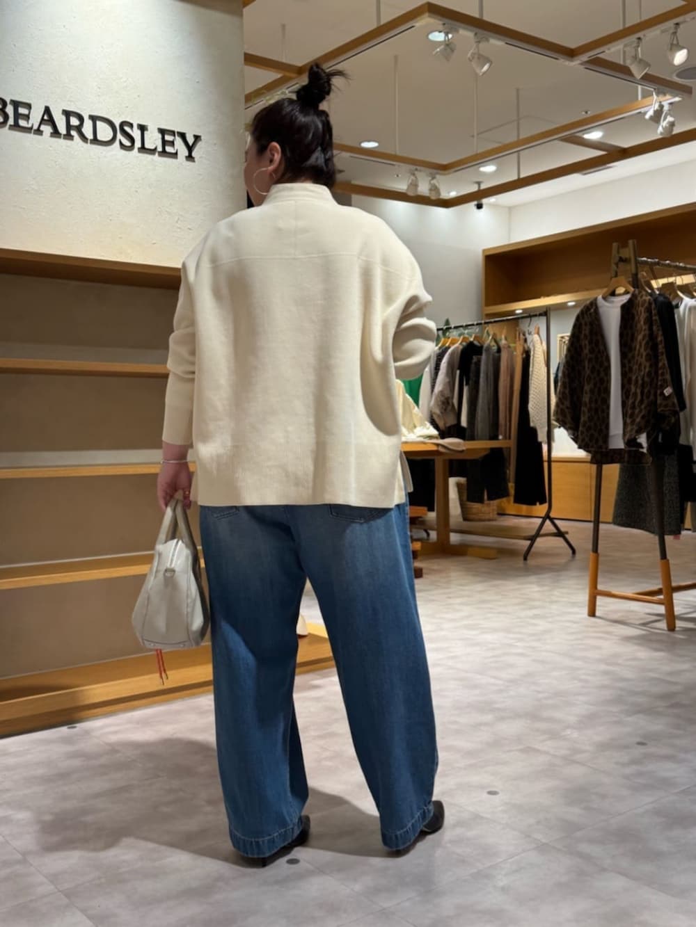 グレー系のボストンバッグ、ブラック系のブーツ、ホワイト系のカーディガン/ボレロを着用したレディースの冬コーディネートの5枚目の写真