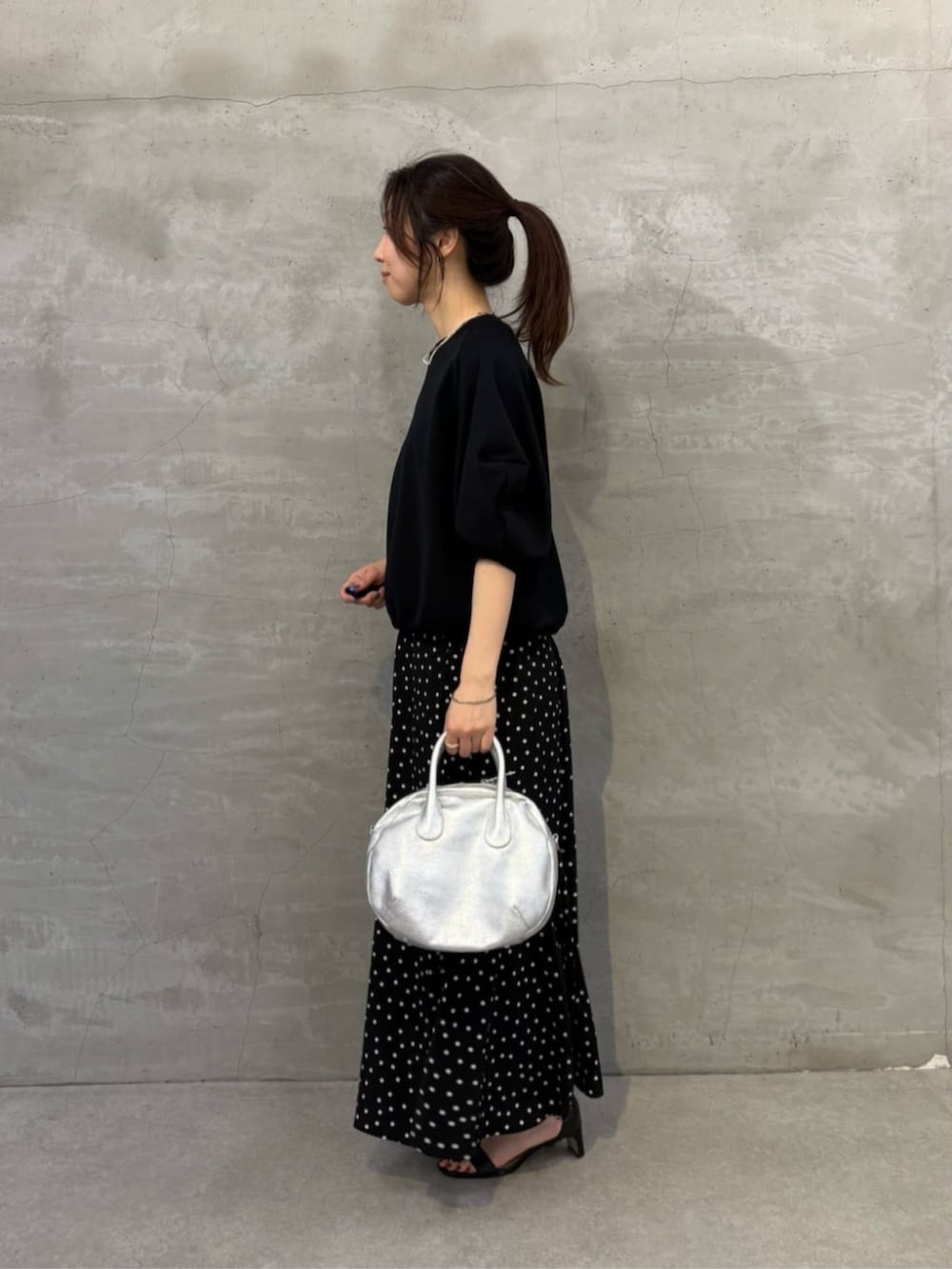 シルバー系のボストンバッグ、ブラック系のスカート、ブラック系のTシャツ/カットソーを着用したレディースの冬コーディネートの2枚目の写真