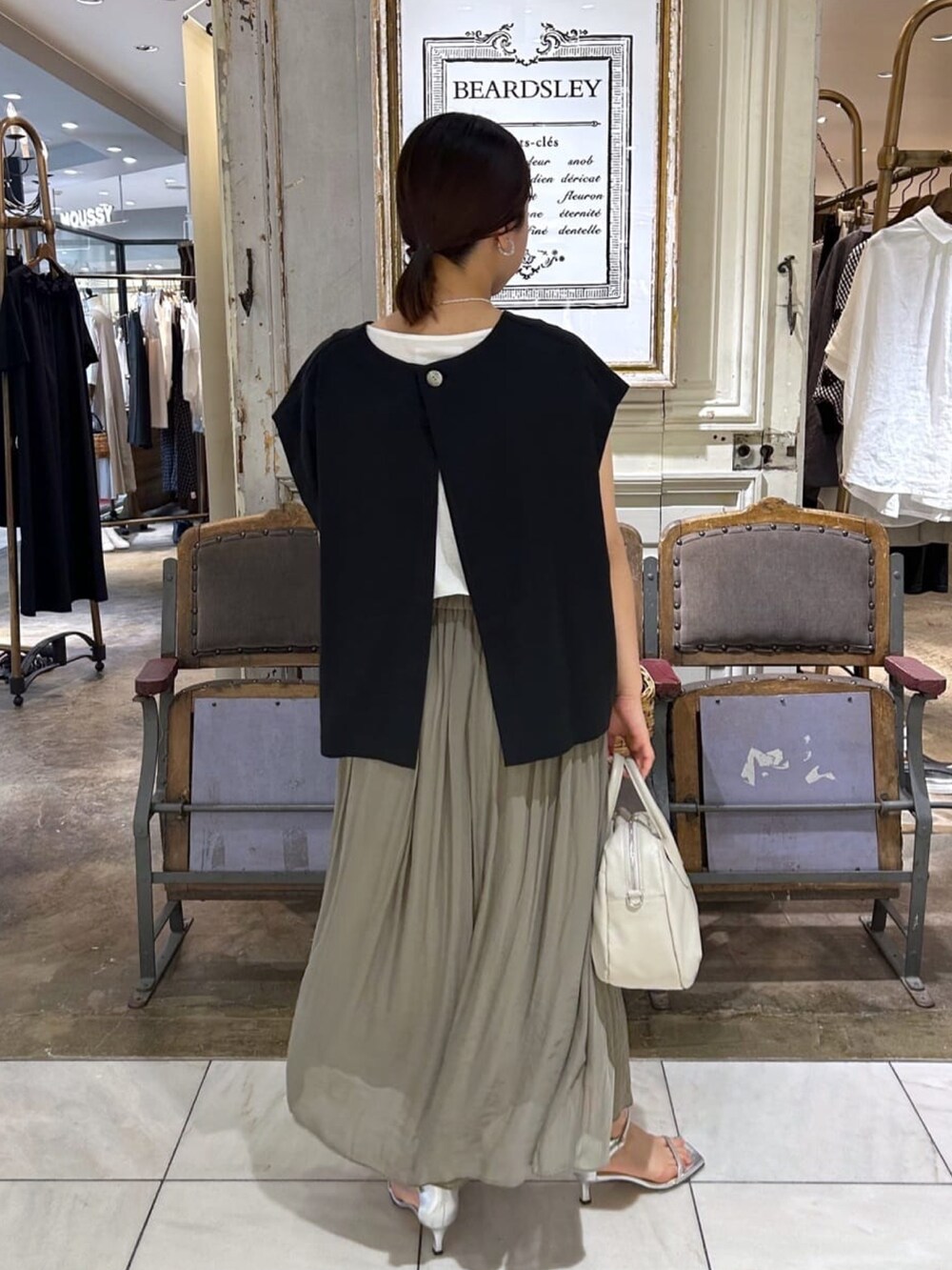 ブルー系のベスト、グレー系のショルダーバッグ、グリーン系のその他パンツを着用したレディースの夏コーディネートの2枚目の写真