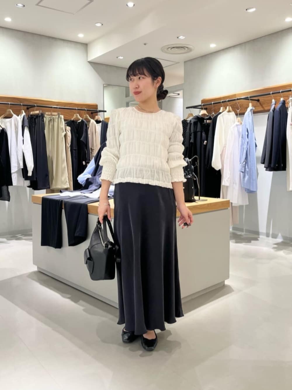 ブラック系のスカート、ブラック系のトートバッグ、ホワイト系のシャツ/ブラウスを着用したレディースの春コーディネートの3枚目の写真