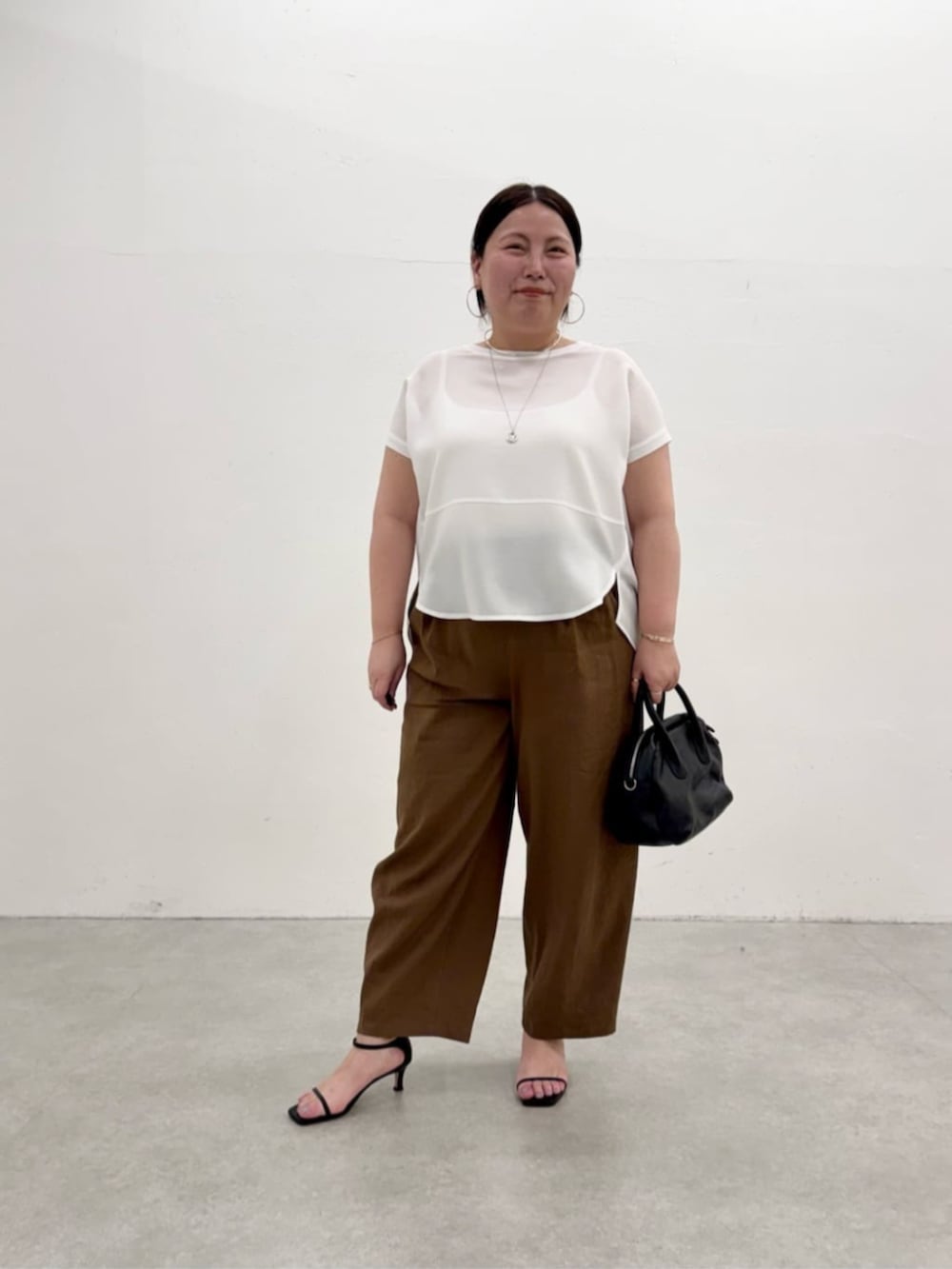 ブラック系のボストンバッグ、ホワイト系のシャツ/ブラウス、ブラウン系のその他パンツを着用したレディースの春コーディネートの3枚目の写真