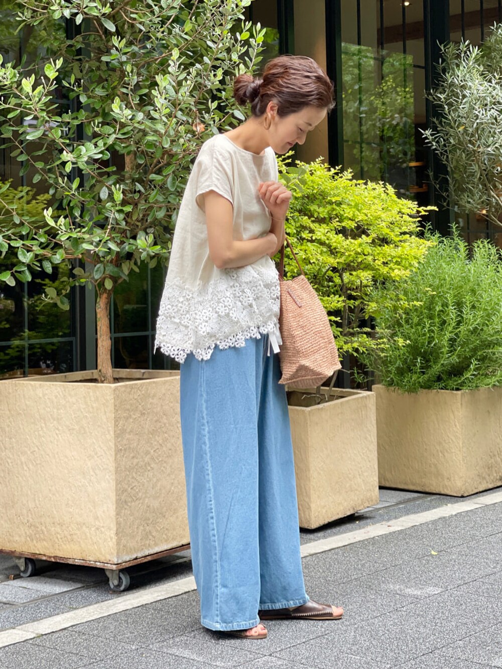 ベージュ系のシャツ/ブラウス、ブルー系のデニムパンツ、ベージュ系のかごバッグを着用したレディースの春コーディネートの2枚目の写真