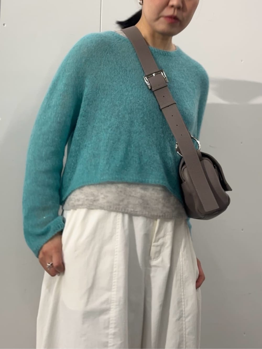 グレー系のショルダーバッグ、ブルー系のニット/セーター、ホワイト系のその他パンツを着用したレディースの夏コーディネートの3枚目の写真