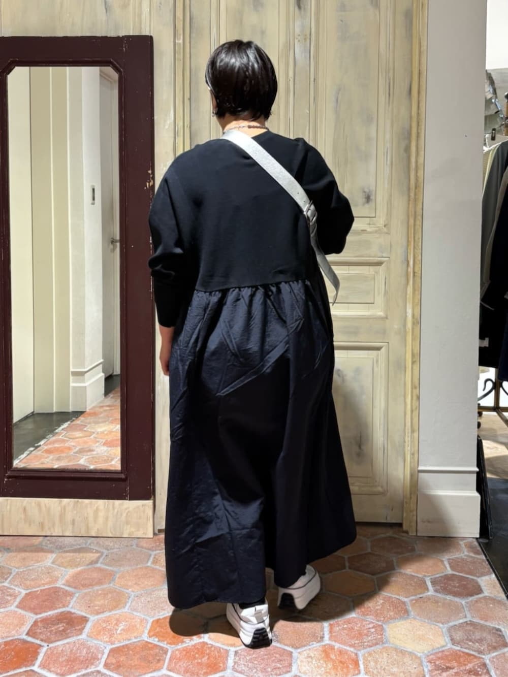 ホワイト系のスニーカー、ブラック系のワンピース、シルバー系のショルダーバッグを着用したレディースの冬コーディネートの4枚目の写真