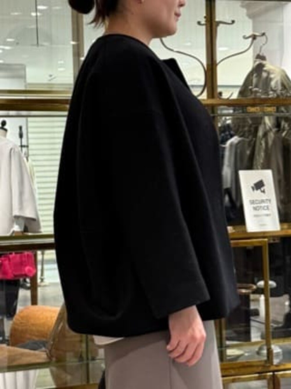 ブラウン系のスカート、ブラック系のノーカラーコートを着用したレディースの冬コーディネートの7枚目の写真