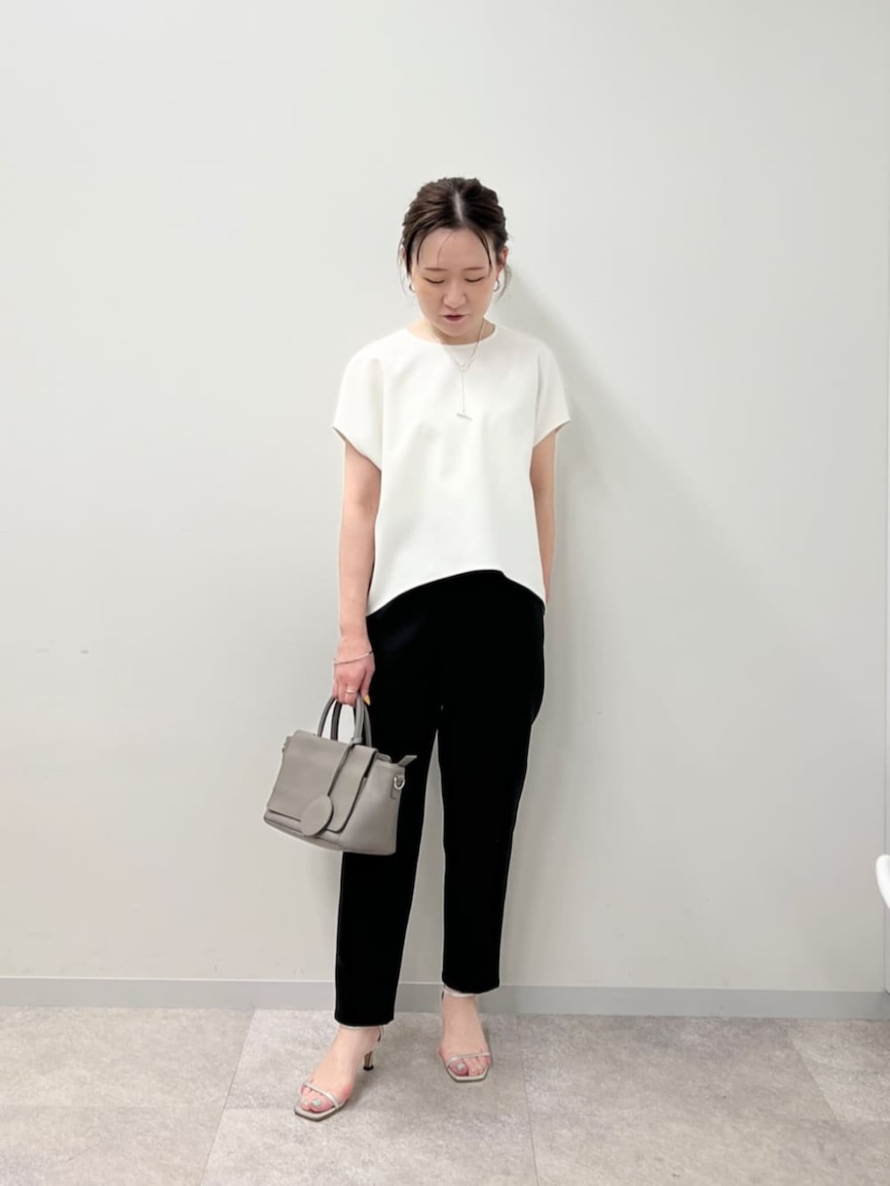 グレー系のハンドバッグ、ブラック系のその他パンツ、ホワイト系のシャツ/ブラウスを着用したレディースの春コーディネートの2枚目の写真