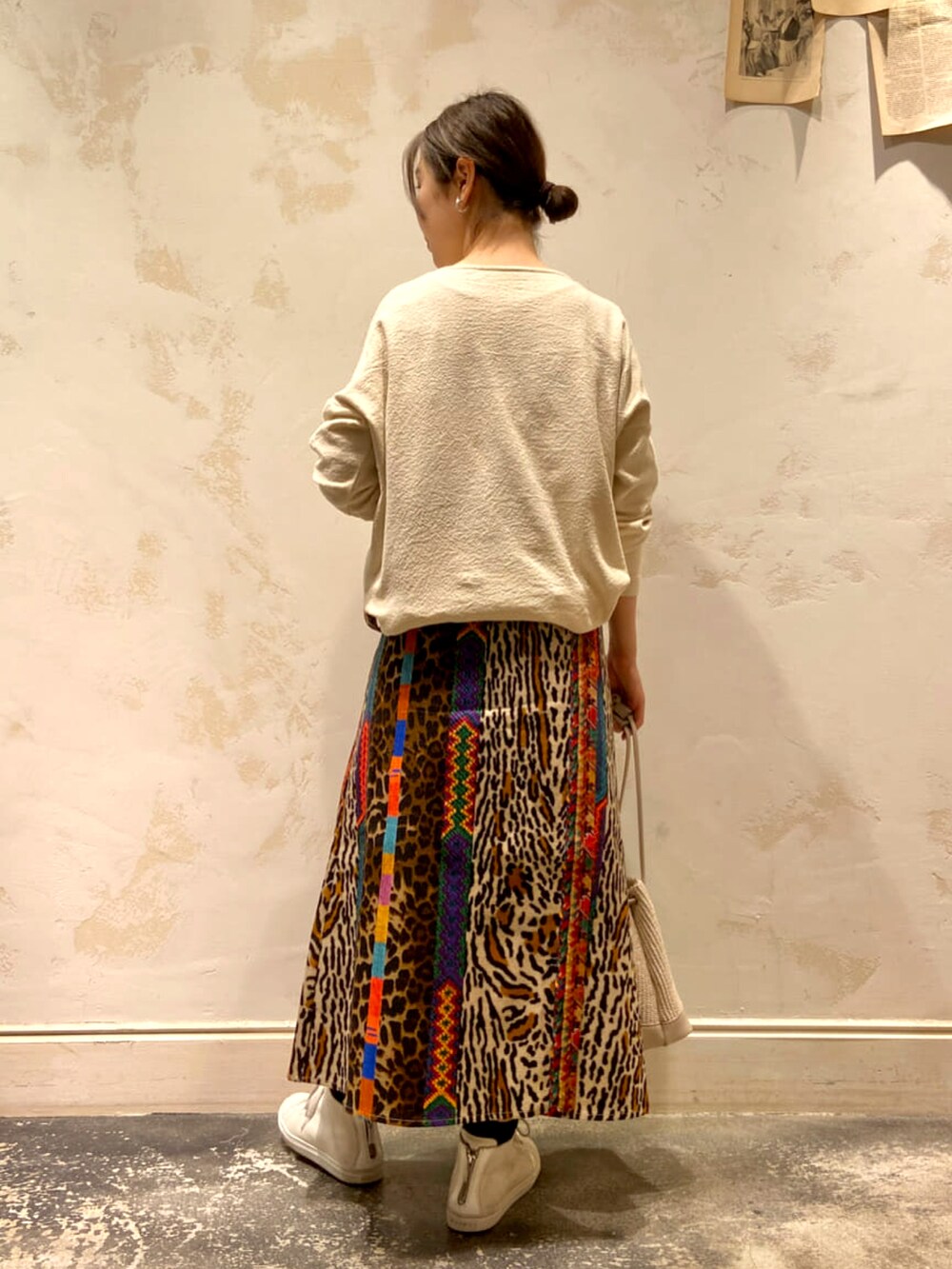 ベージュ系のトートバッグ、ホワイト系のニット/セーター、ホワイト系のスニーカーを着用したレディースの春コーディネートの3枚目の写真