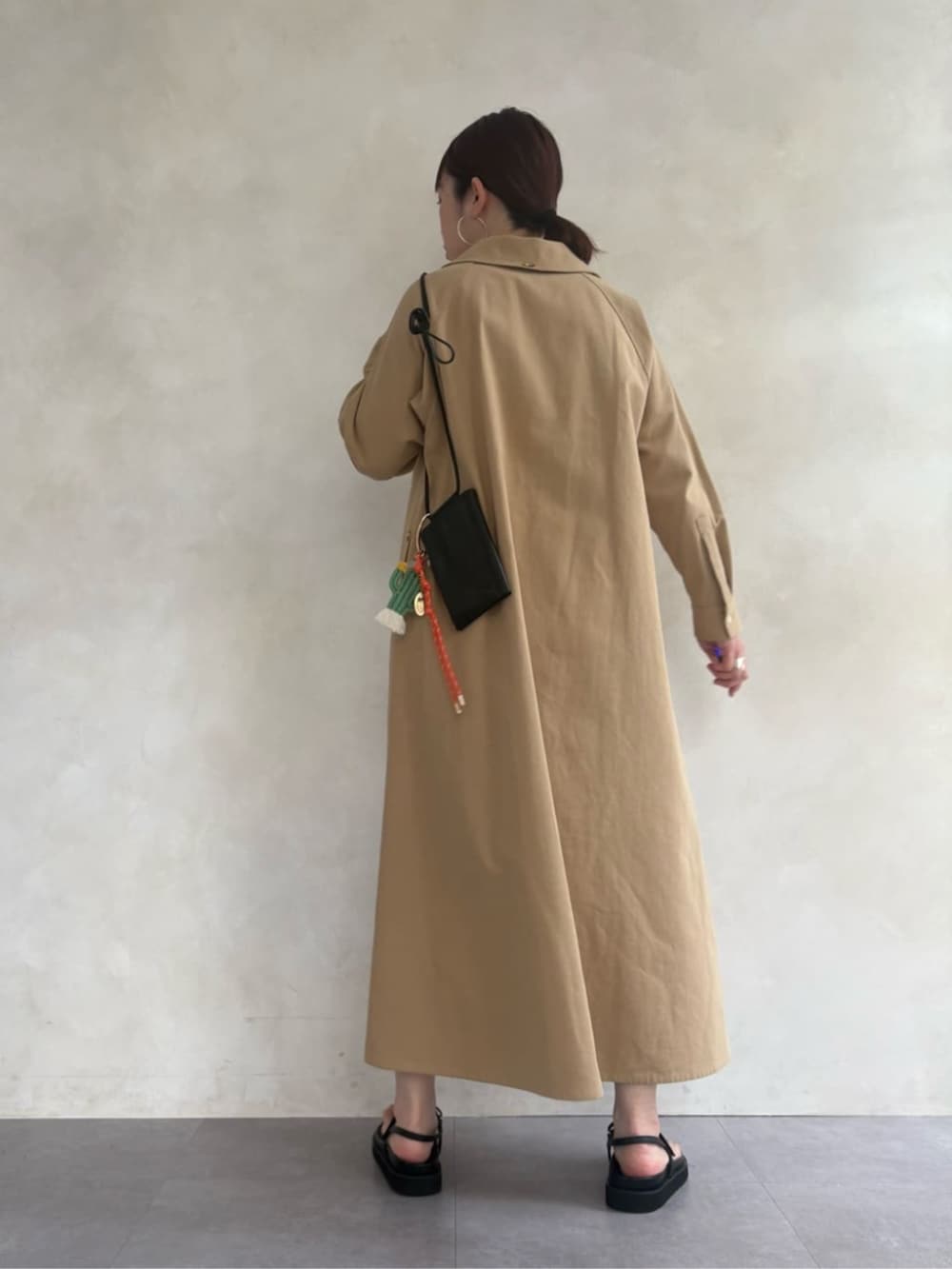 ブラック系のサンダル、ブラック系のショルダーバッグ、ベージュ系のワンピースを着用したレディースの春コーディネートの4枚目の写真