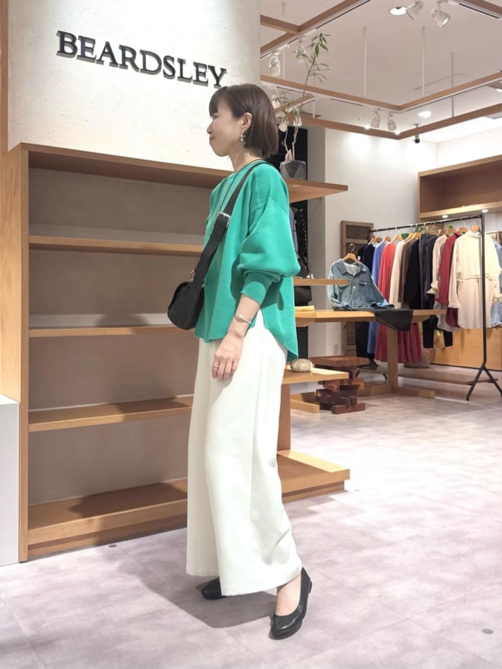 ブラック系のショルダーバッグ、ホワイト系のその他パンツ、グリーン系のTシャツ/カットソーを着用したレディースの春コーディネートの3枚目の写真