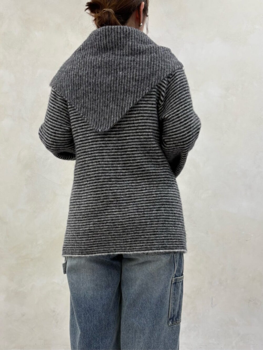 ブルー系のデニムパンツ、ブラック系のブーツ、ブラック系のニット/セーターを着用したレディースの秋コーディネートの5枚目の写真