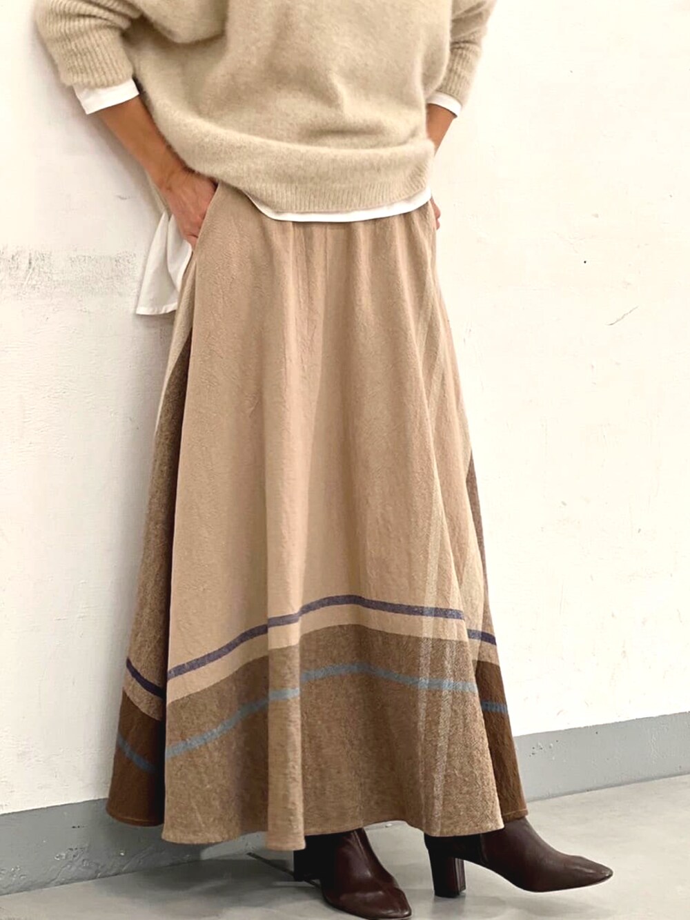 ホワイト系のニット/セーター、ホワイト系のTシャツ/カットソー、ベージュ系のスカートを着用したレディースの秋コーディネートの4枚目の写真