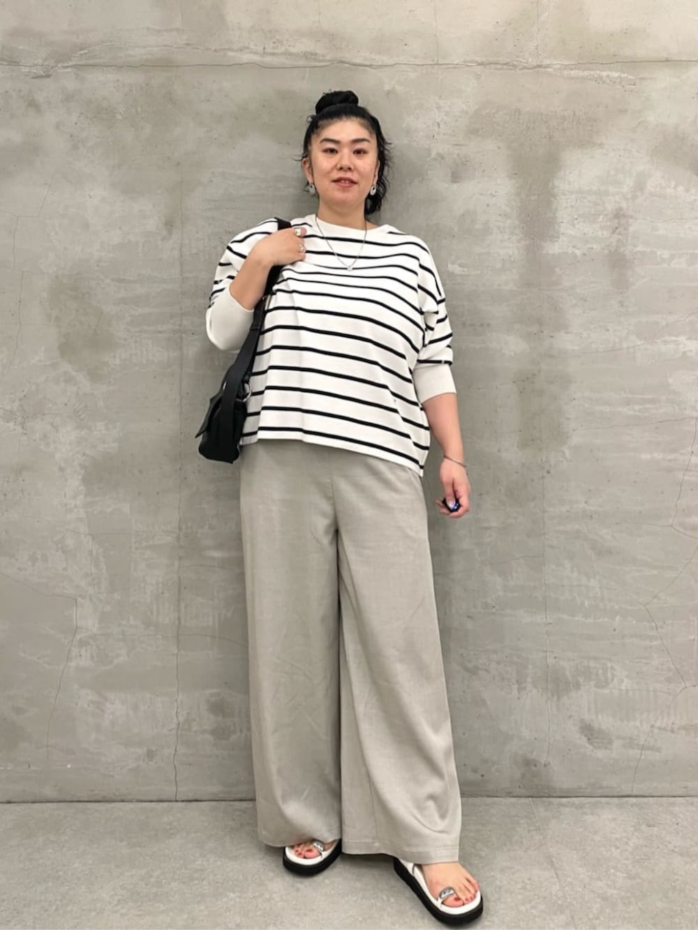 ブラック系のショルダーバッグ、ホワイト系のニット/セーター、ホワイト系のサンダルを着用したレディースの冬コーディネートの2枚目の写真