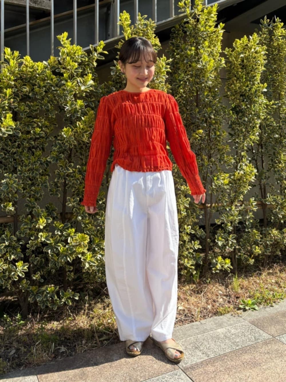 オレンジ系のシャツ/ブラウス、ホワイト系のその他パンツを着用したレディースの春コーディネートの2枚目の写真