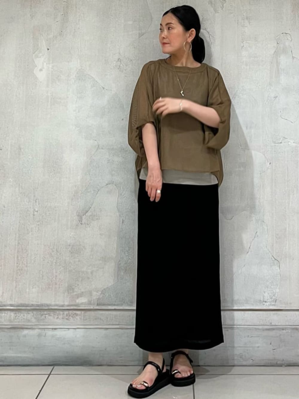ブラック系のショルダーバッグ、ブラック系のスカート、イエロー系のTシャツ/カットソーを着用したレディースの春コーディネートの6枚目の写真