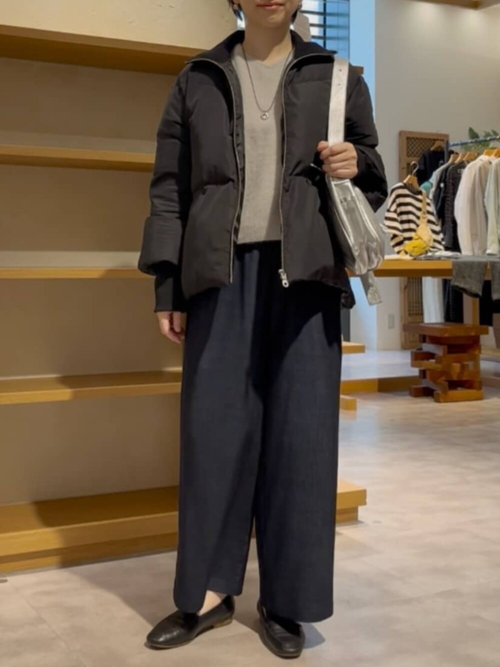 ブルー系のその他パンツ、グレー系のニット/セーター、ブラック系のダウンジャケット/コートを着用したレディースの冬コーディネートの2枚目の写真