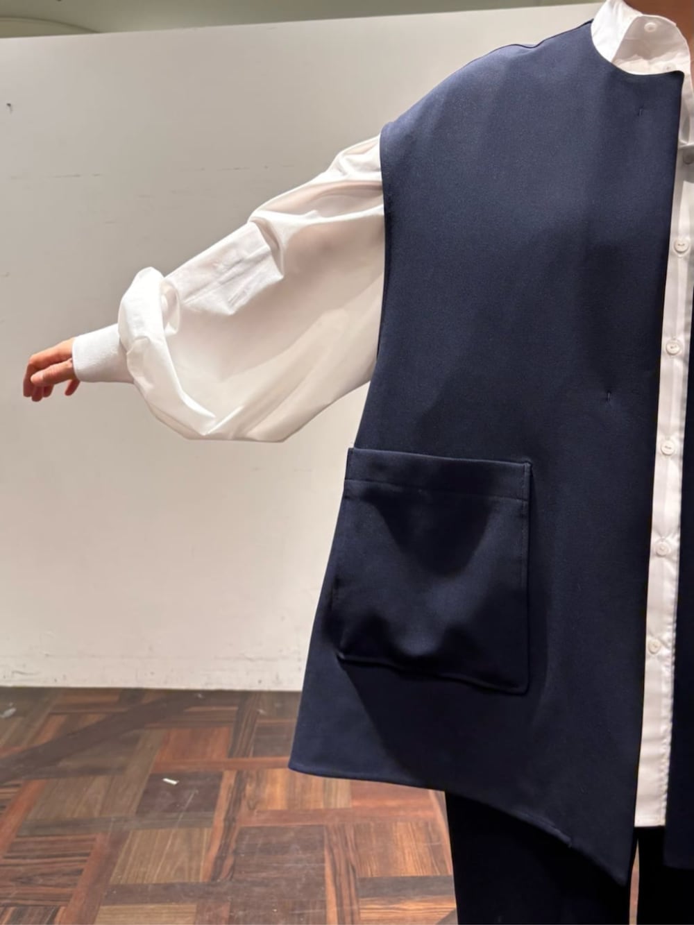 ブラック系のボストンバッグ、ブルー系のベスト、ホワイト系のシャツ/ブラウスを着用したレディースの冬コーディネートの6枚目の写真