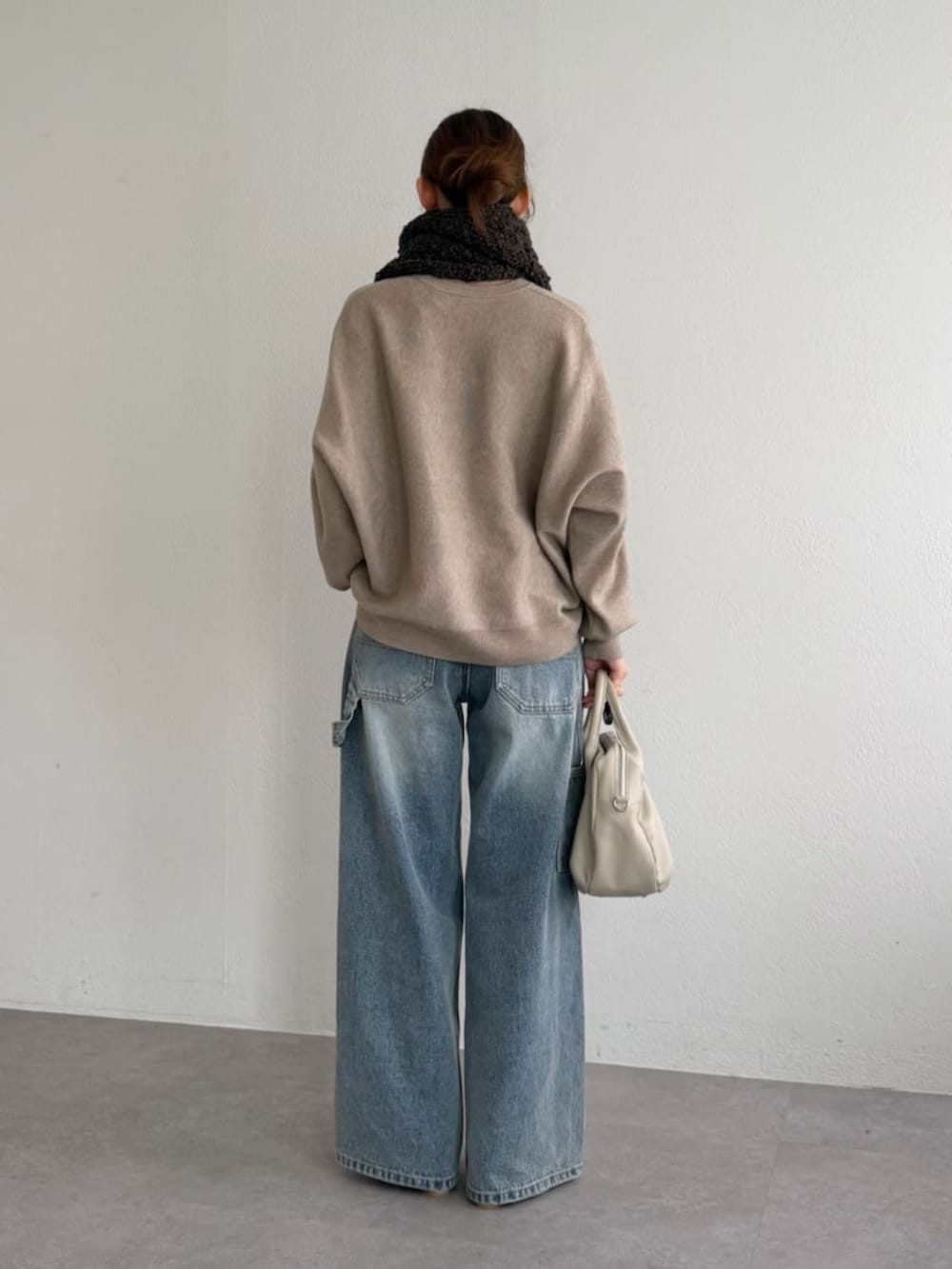 ブルー系のデニムパンツ、ブラウン系のニット/セーター、ブラウン系のマフラーを着用したレディースの秋コーディネートの4枚目の写真
