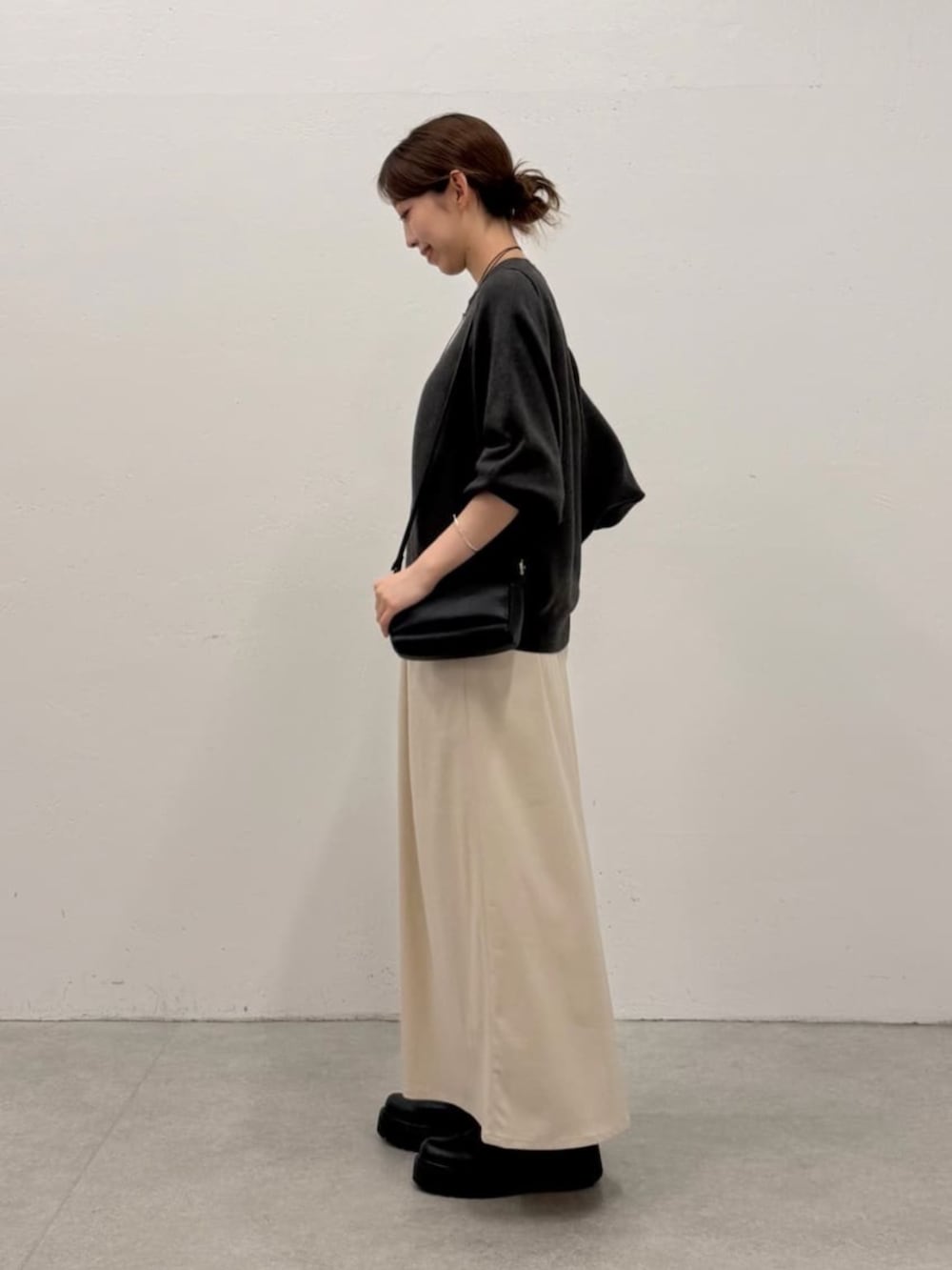 ベージュ系のスカート、グレー系のニット/セーターを着用したレディースの夏コーディネートの2枚目の写真