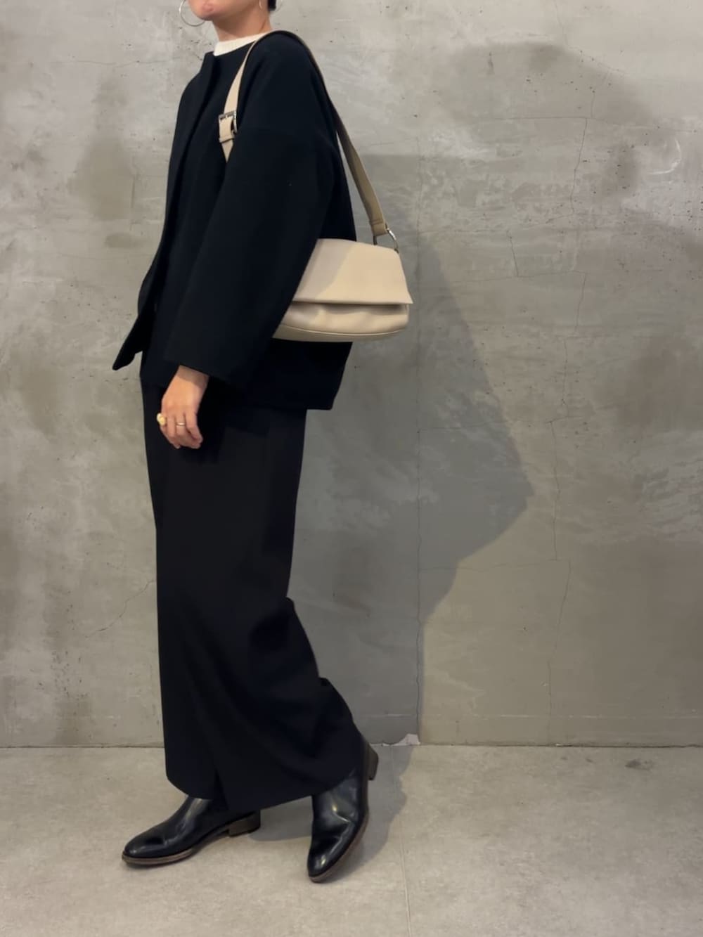 ブラック系のノーカラーコート、ブラック系のその他パンツ、ホワイト系のショルダーバッグを着用したレディースの冬コーディネートの4枚目の写真