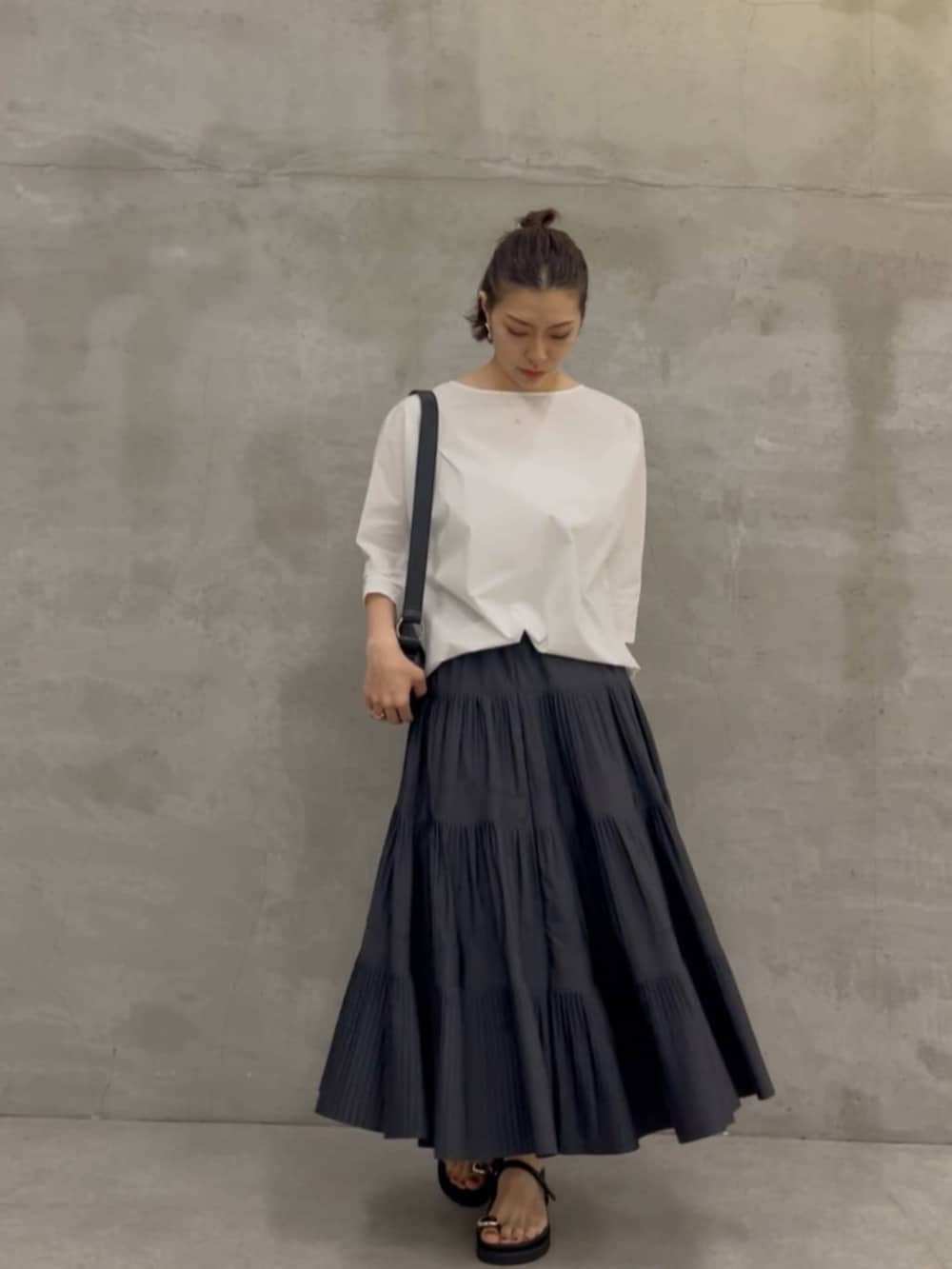 グレー系のスカート、ブラック系のショルダーバッグ、ホワイト系のシャツ/ブラウスを着用したレディースの春コーディネートの2枚目の写真