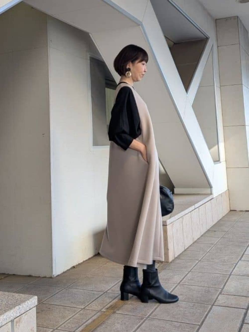 ブラック系のシャツ/ブラウス、ブラウン系のジャンパースカート、シルバー系のネックレスを着用したレディースの冬コーディネートの2枚目の写真