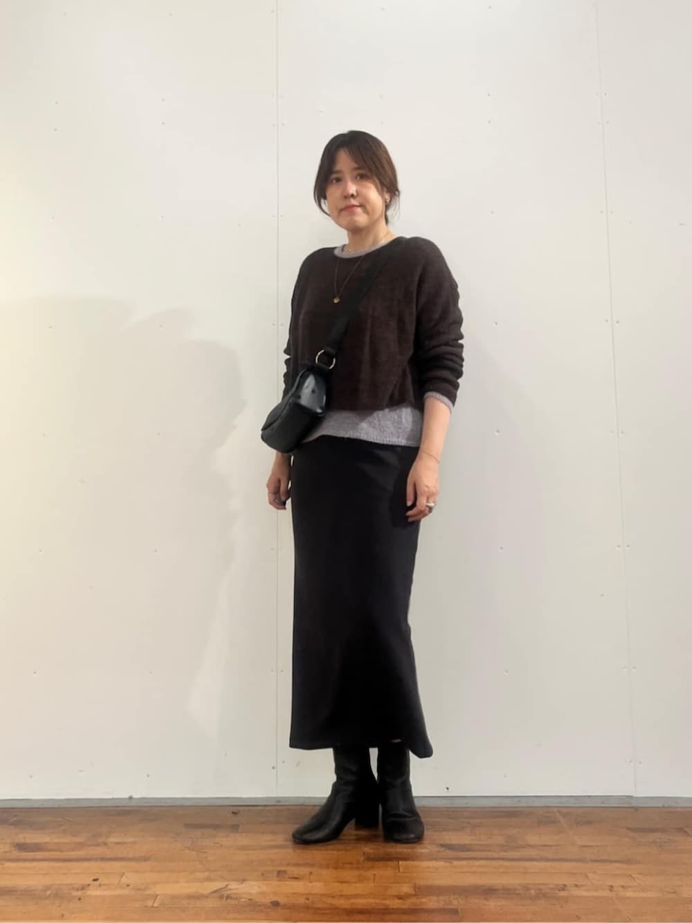 グレー系のスカート、ブラック系のショルダーバッグ、ブラウン系のニット/セーターを着用したレディースの夏コーディネートの3枚目の写真