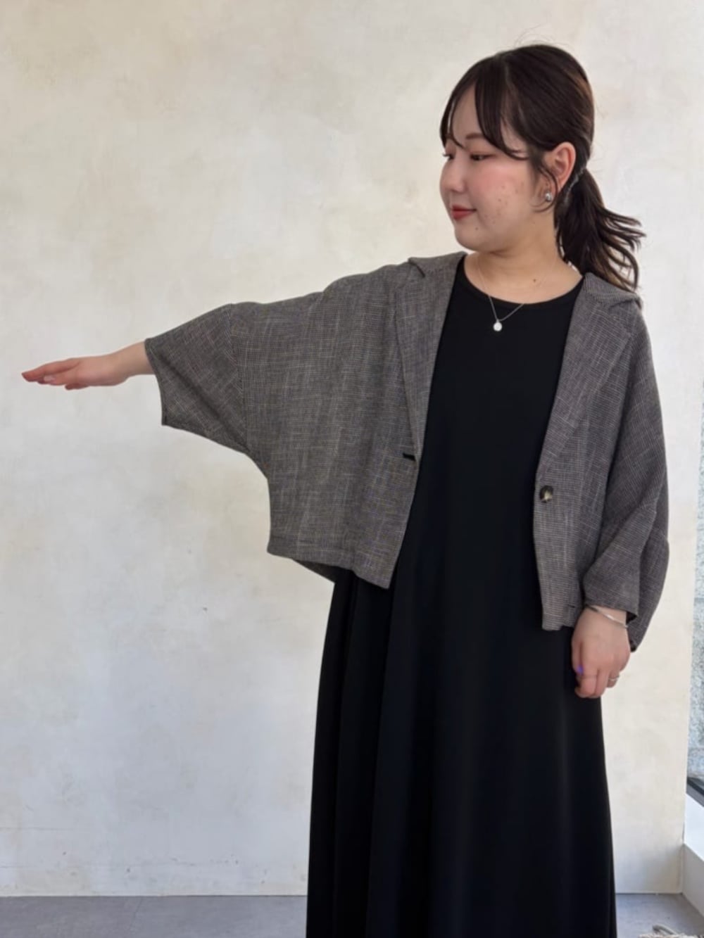 ブラック系のワンピース、ベージュ系のテーラードジャケットを着用したレディースの春コーディネートの4枚目の写真